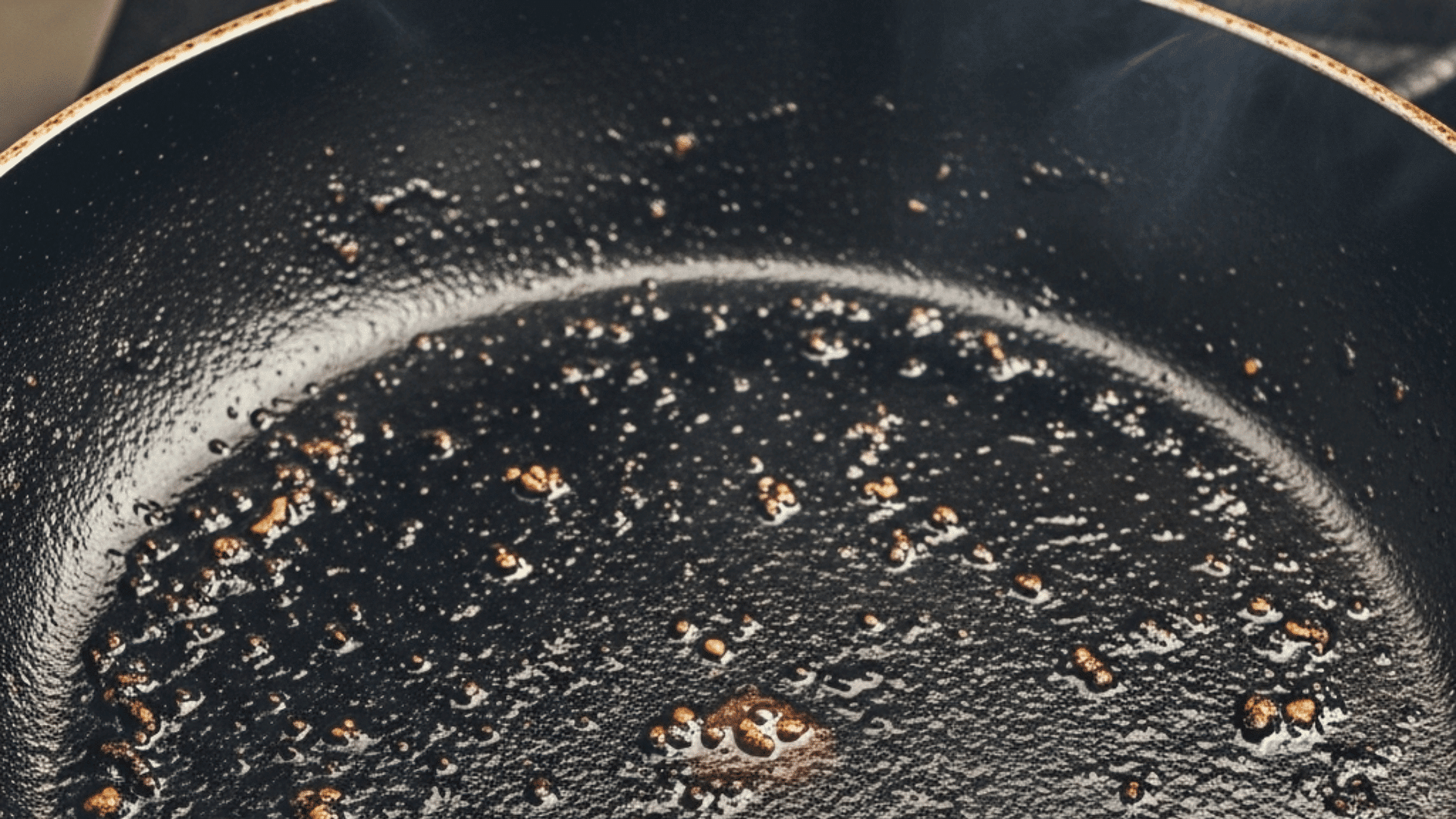 A frying pan containing dark, used cooking oil, suggesting common unhealthy kitchen practices
